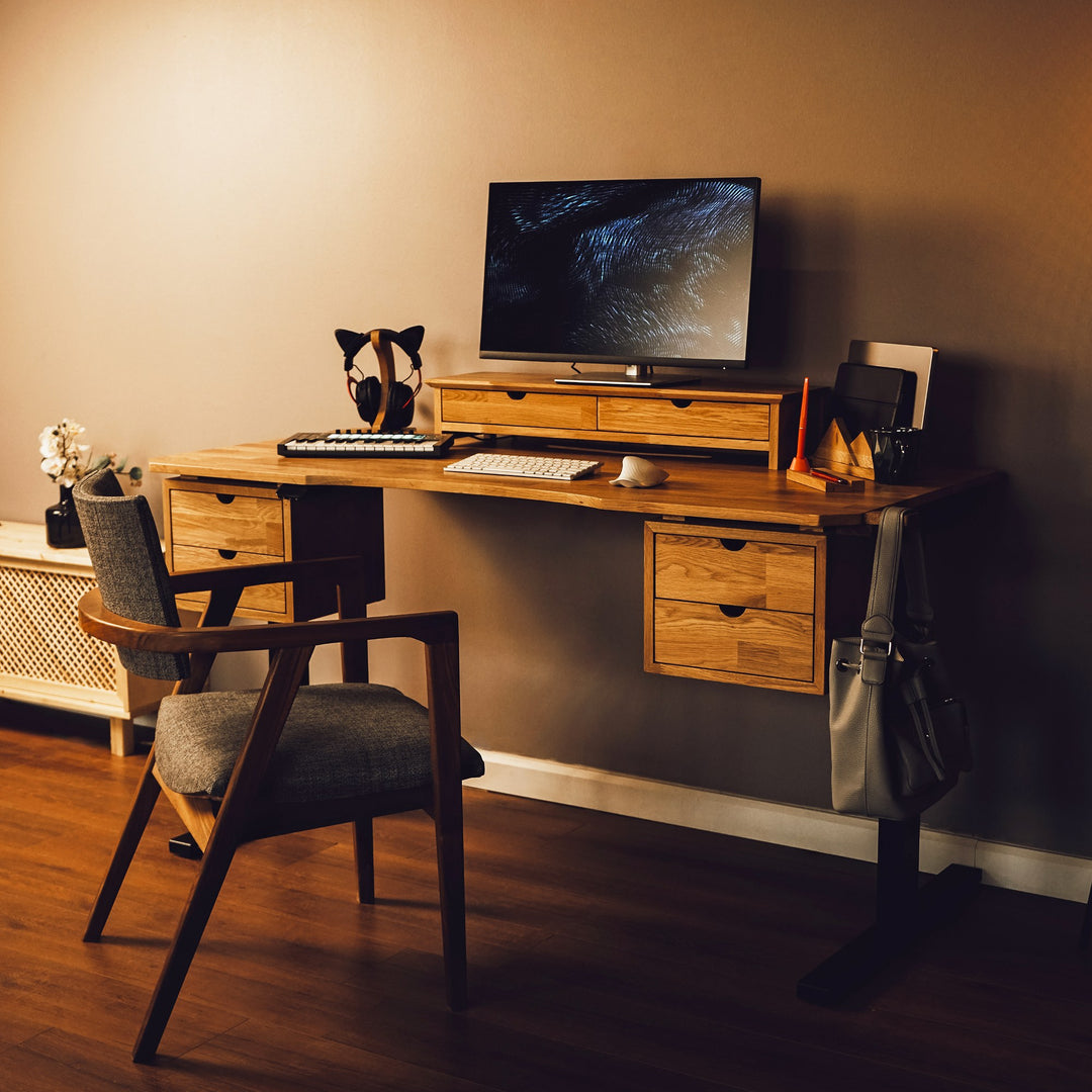 A wood studio desk workstation with storage and monitor stand, featuring a computer and chair in a well-lit room.