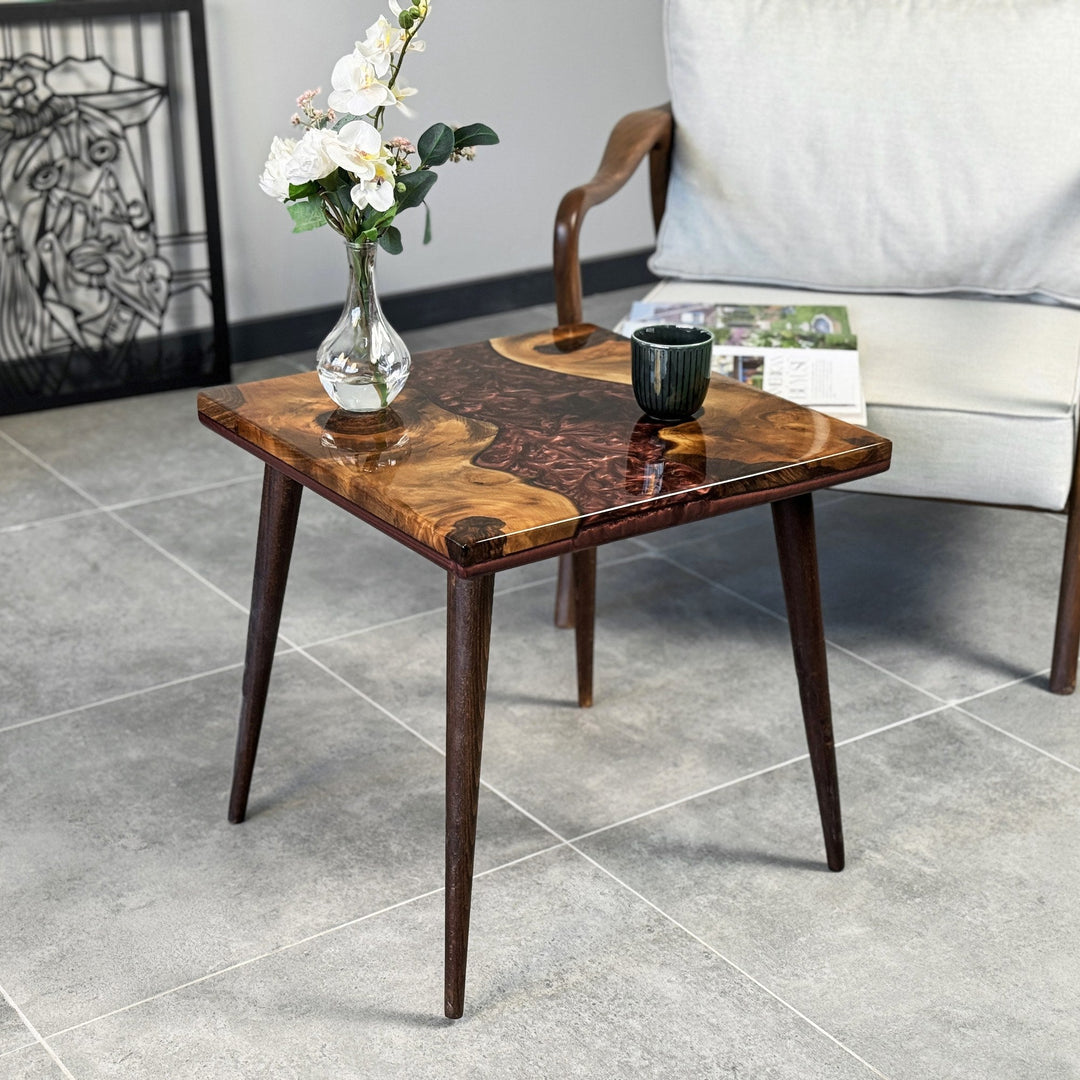 Walnut side table with epoxy river design, featuring a vase on top, set in a cozy interior space.