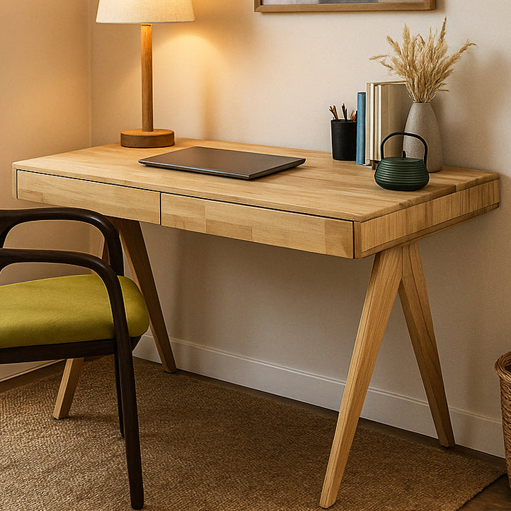 Light oak desk with two drawers and V-shaped legs, three-quarter view with a green-seat chair at the left