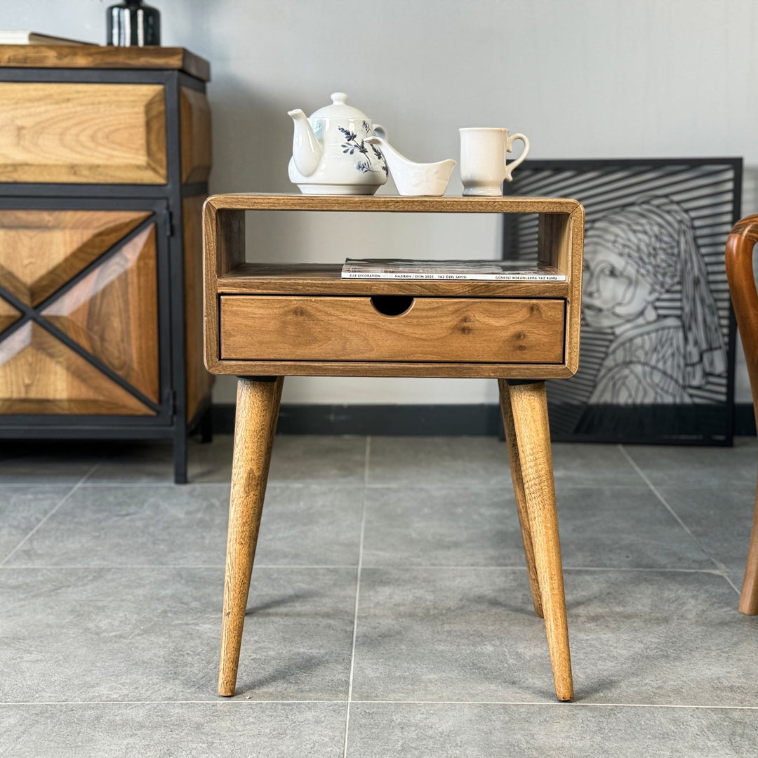 A walnut side table with a drawer, featuring a cup placed on its surface.