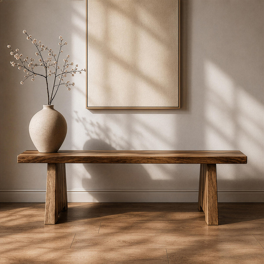 Minimalist solid walnut slab bench with trapezoid legs, front view against a wall with a framed canvas