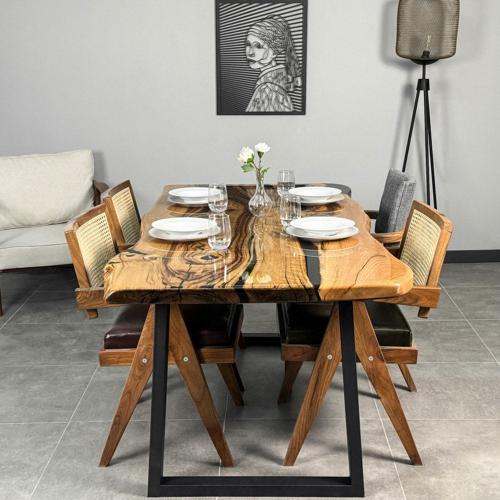 Live edge chestnut dining table with a glossy golden slab, wavy natural edges and dark filled cracks on a black metal trapezoid base with four cane-back chairs