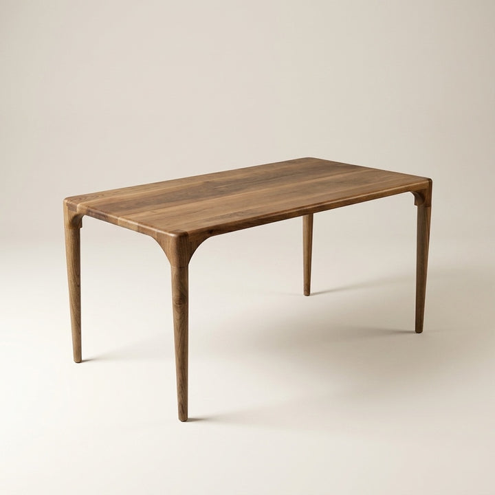 Oslo solid walnut dining table on a plain background, with tapered round legs and a smooth rounded edge
