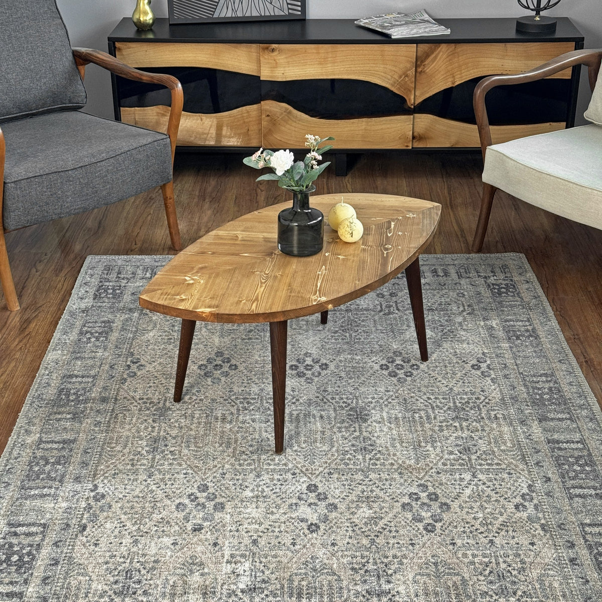 Leaf shaped coffee table with a medium-brown knotty top, front view on a patterned rug