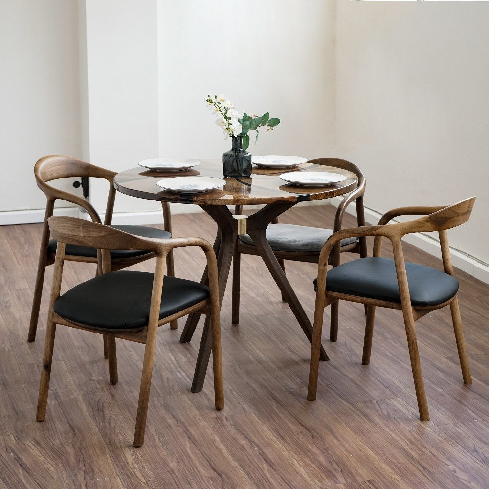 Round walnut dining table with epoxy swirl, high corner view with wooden armchairs around it