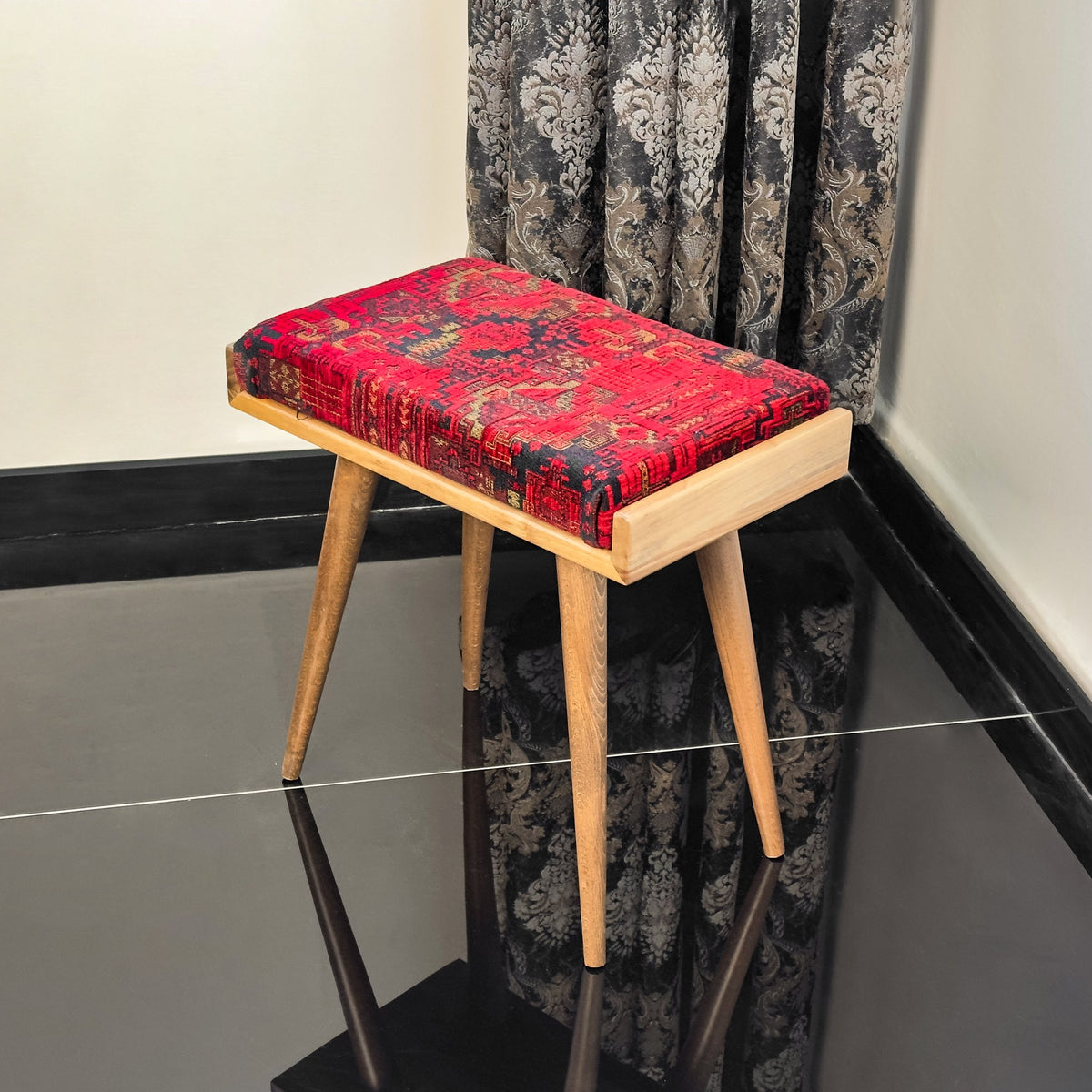 Keyboard bench with a red patterned cushion and a wooden frame, seen from a three-quarter angle