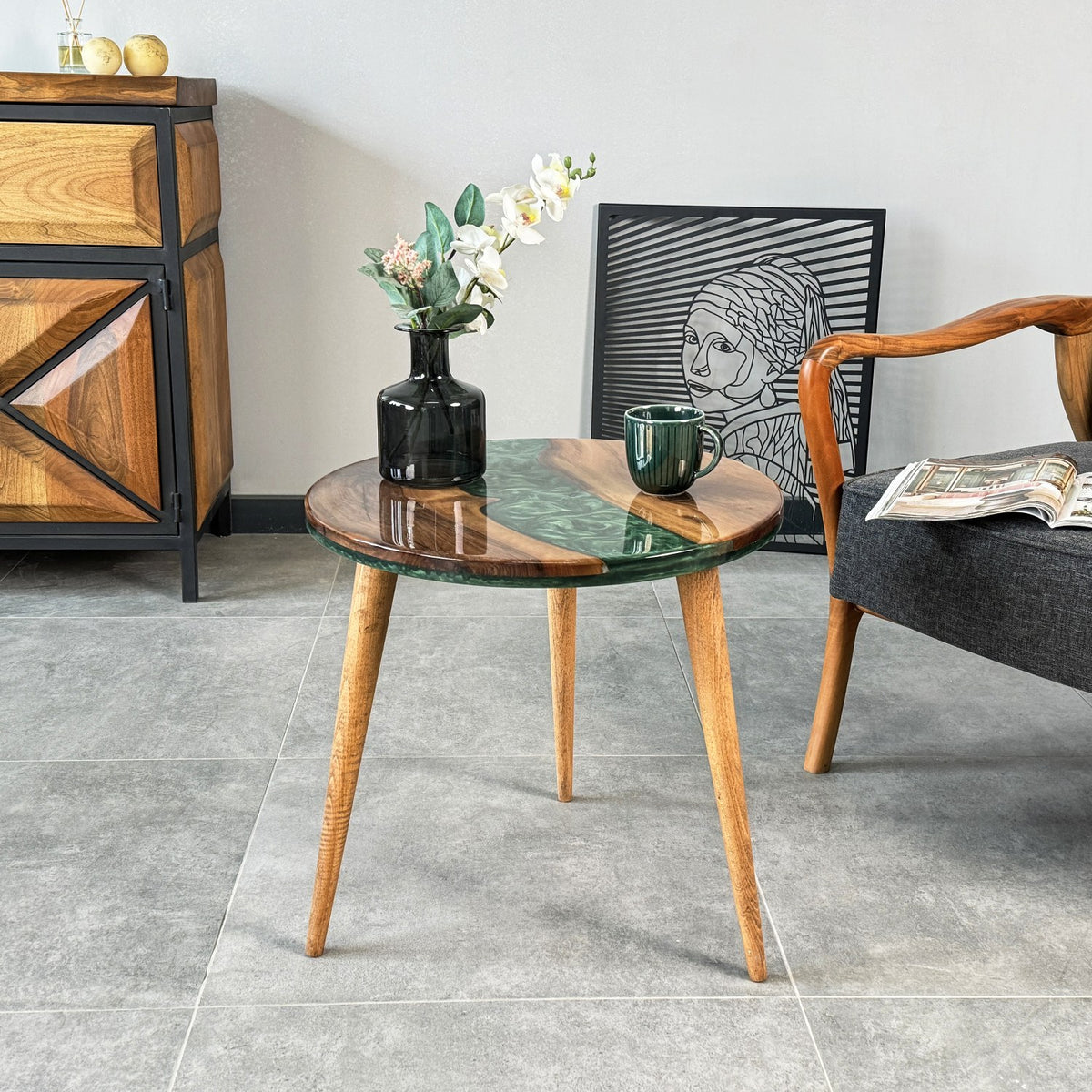 Side view of the round walnut epoxy table with three tapered legs on a gray tile floor