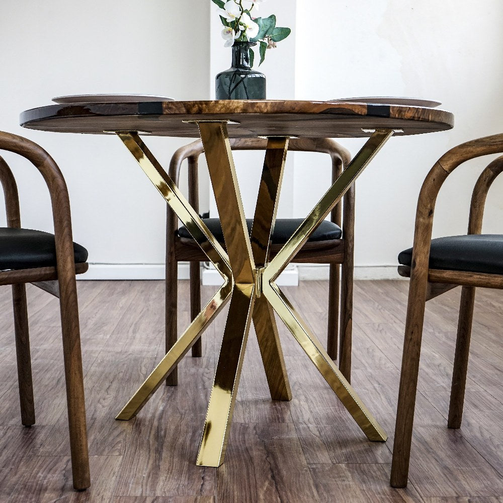 Close-up of the polished gold crossed legs under the round walnut epoxy dining table