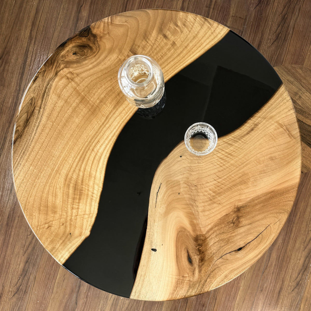 Top-down view of the round walnut bar table with a black epoxy river across the top
