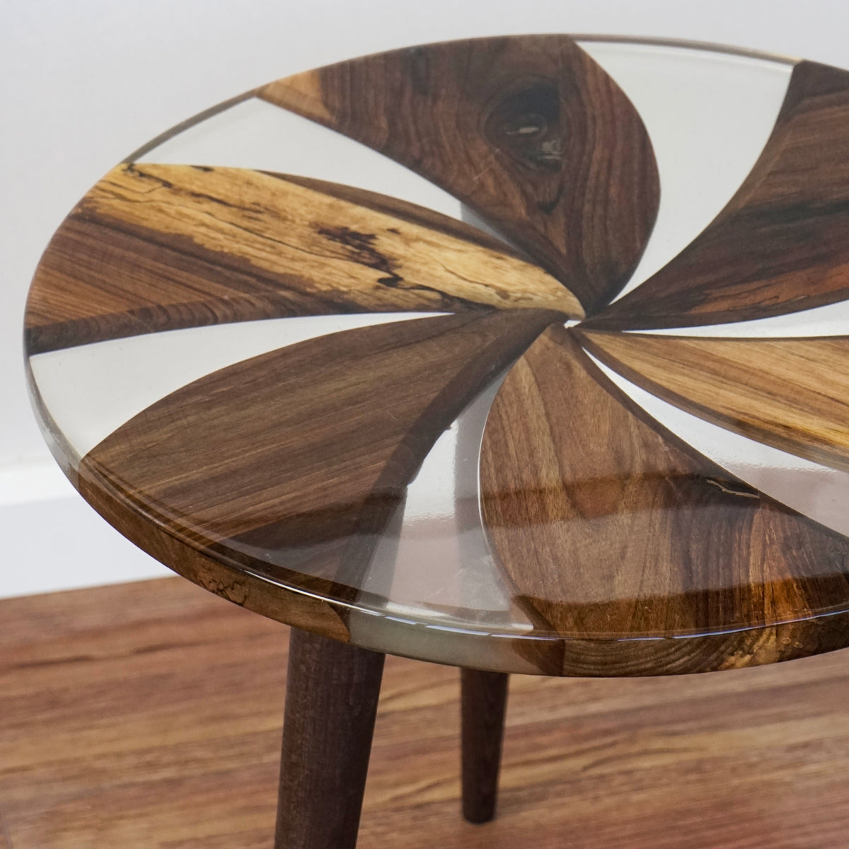 Edge close-up of the round walnut side table top showing clear epoxy between the walnut sections