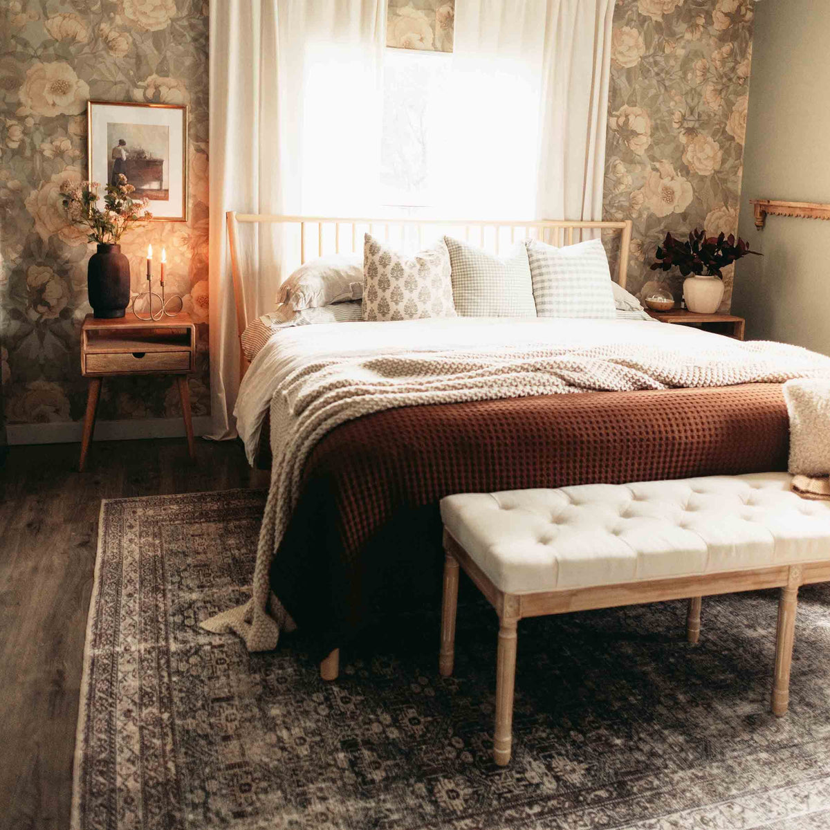 Walnut nightstand with drawer and open shelf at the far left of a made bed, wide bedroom view