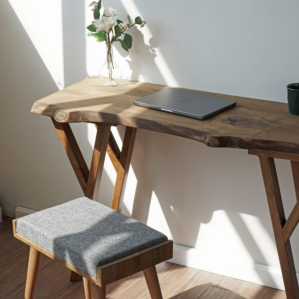 Close-up of the live edge desktop corner with a laptop and a gray stool pulled up to the desk