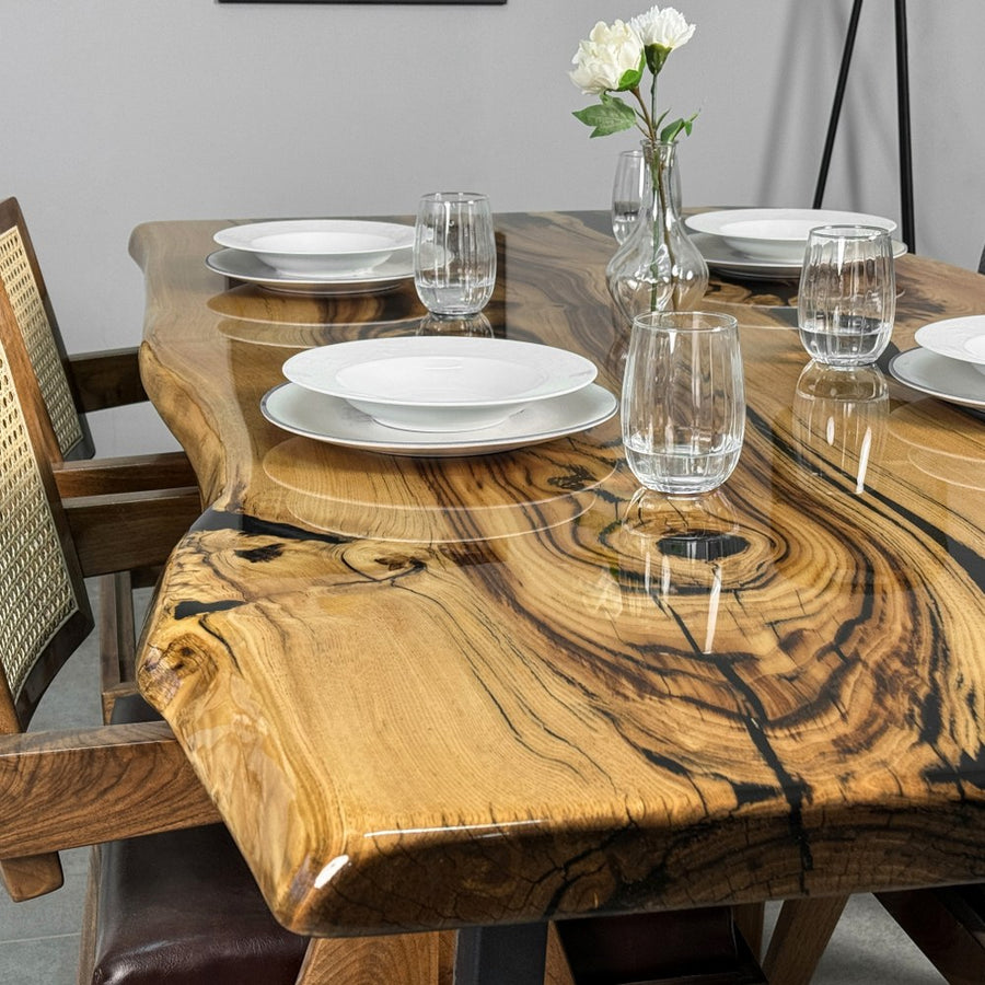 Close-up of the chestnut live edge dining table top with a black epoxy seam, plates and a bud vase