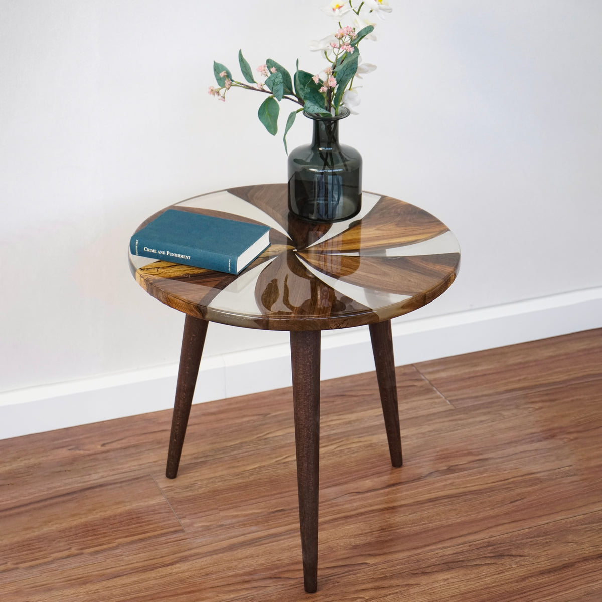 Round walnut side table with epoxy windmill pattern, slightly raised front view on a wood floor