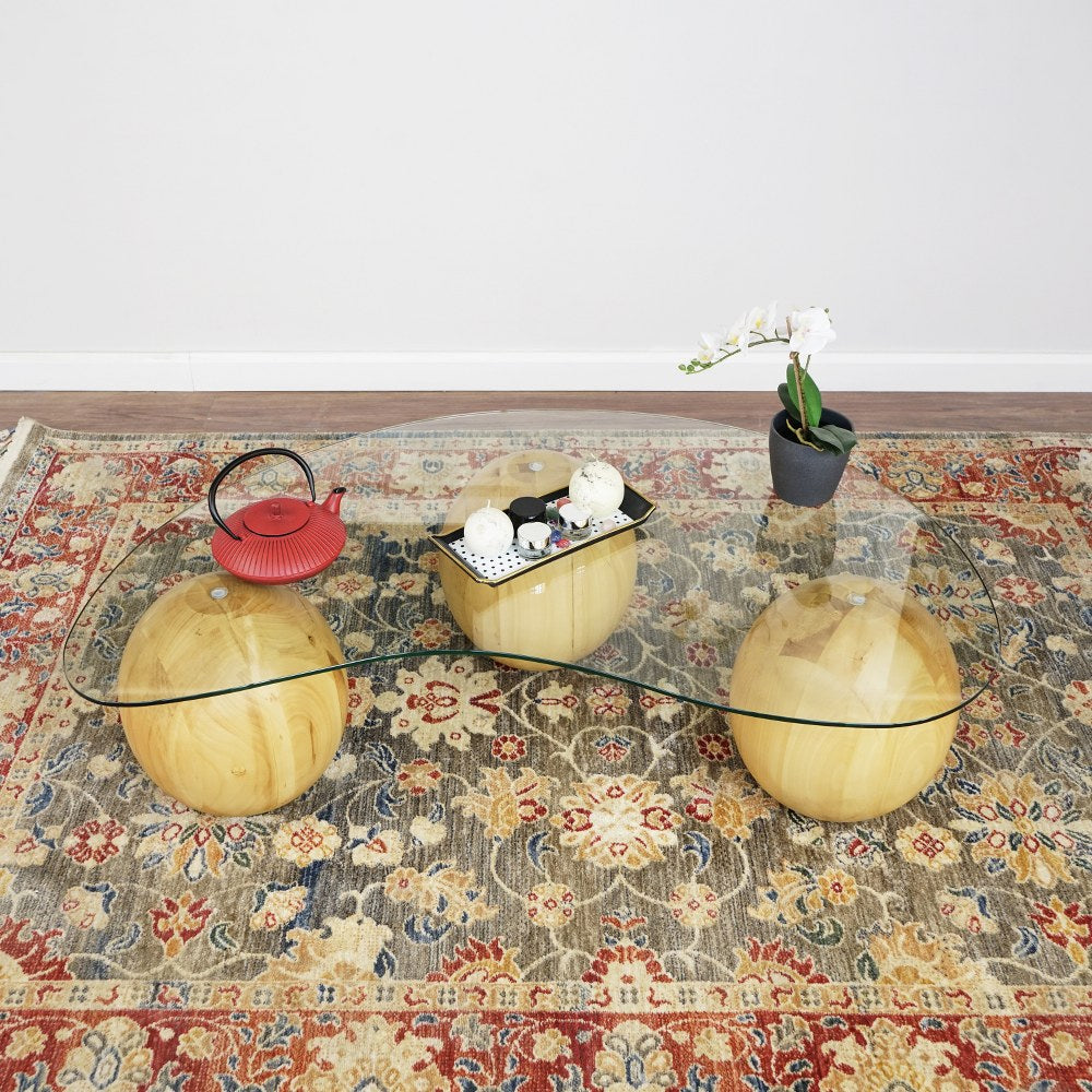 Top view of the bean shaped glass coffee table on three wooden balls over a rug