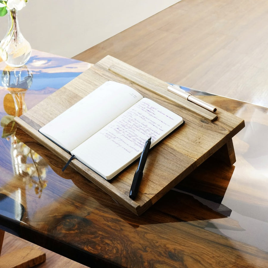 Solid walnut writing slope holding an open notebook and a pen, angled view on a table
