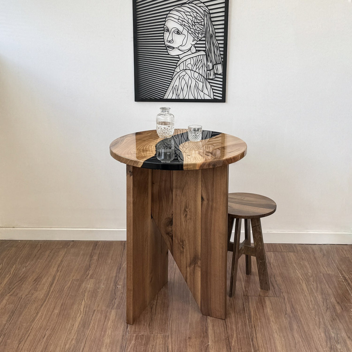 Front view of the walnut round bar table with a black epoxy river and a wooden stool beside it