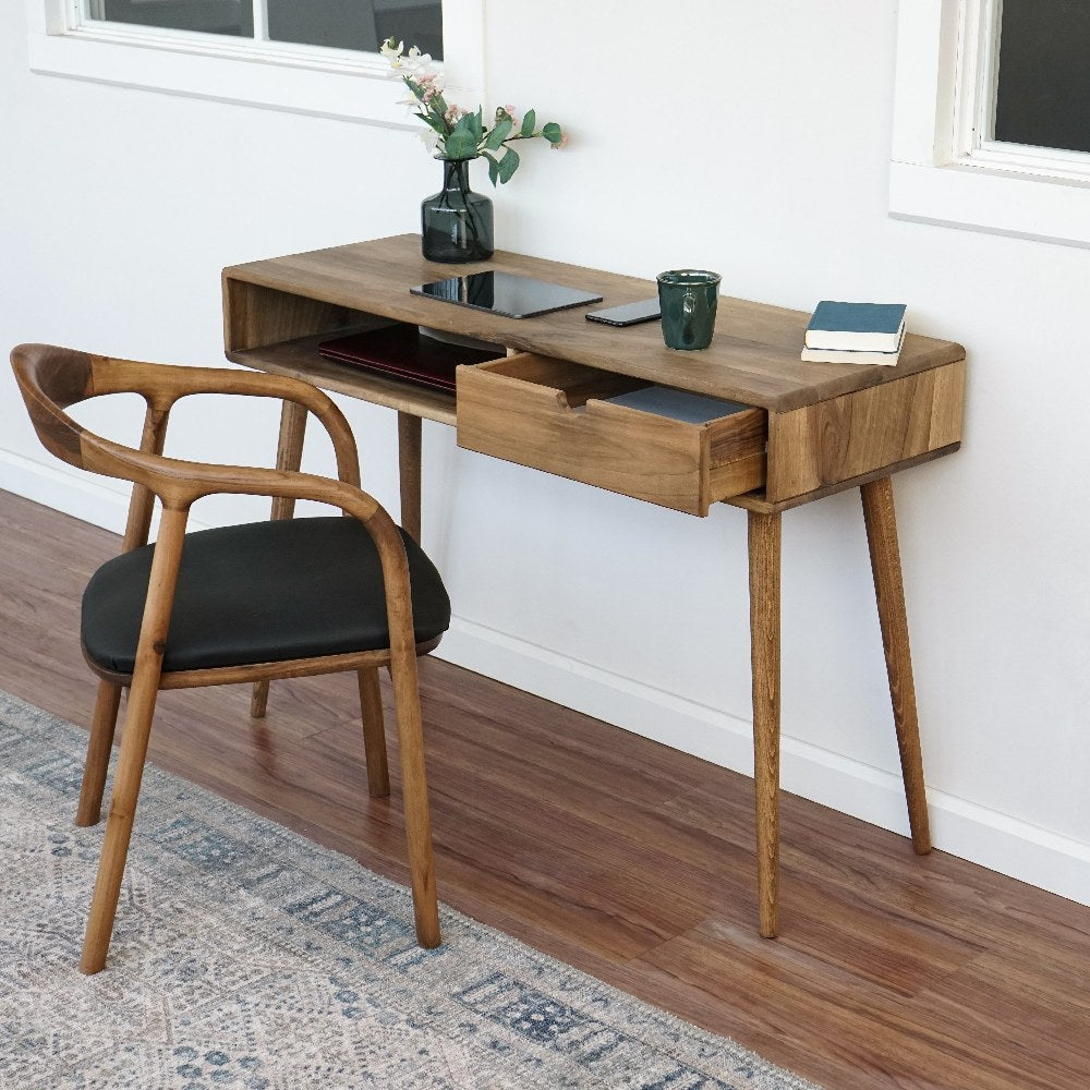 Walnut desk with an open drawer seen from the side with the armchair at the left on a rug