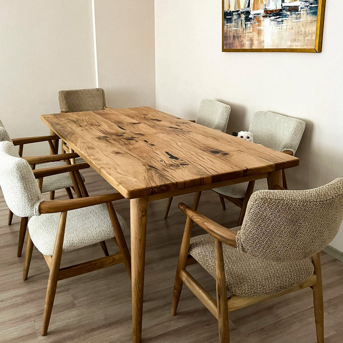 Solid oak dining table with dark knots and weathered grain, surrounded by gray armchairs