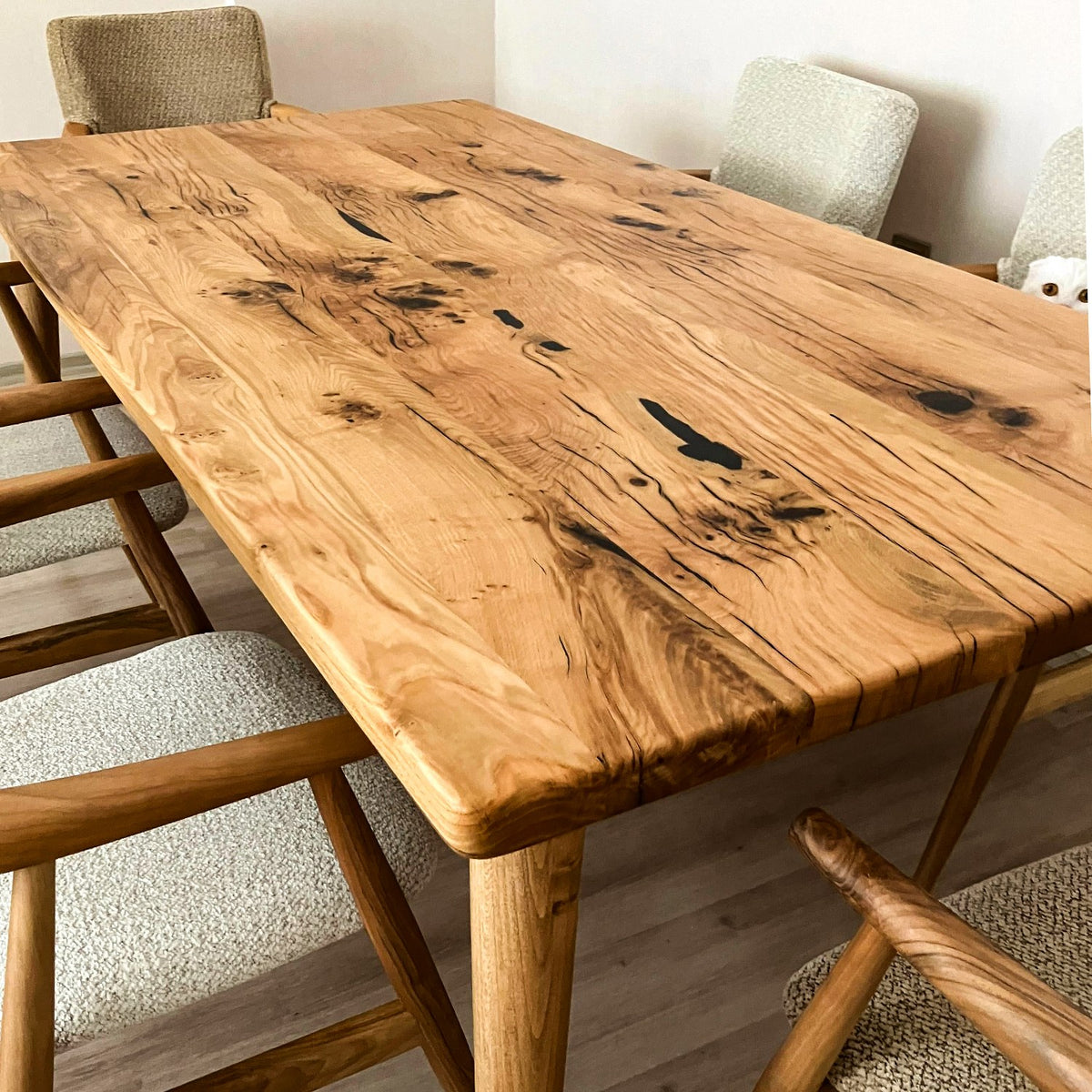 Close-up of the oak dining table top showing dark knots, live grain and a rounded edge