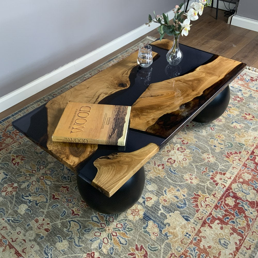 Corner view of the walnut coffee table with a black epoxy river top over a patterned rug