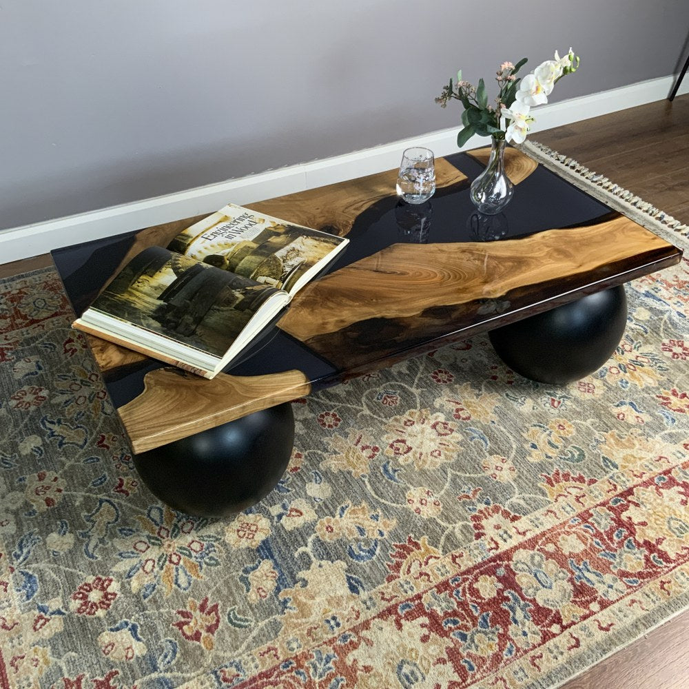 Walnut and black epoxy coffee table seen from the end with one ball leg beneath the corner