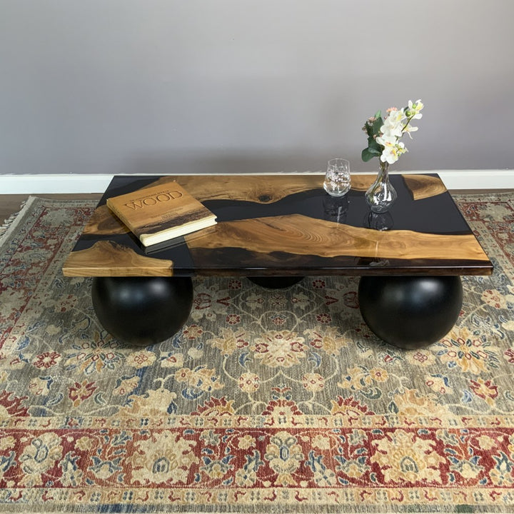Front view from a distance of the black epoxy river coffee table and its three ball legs