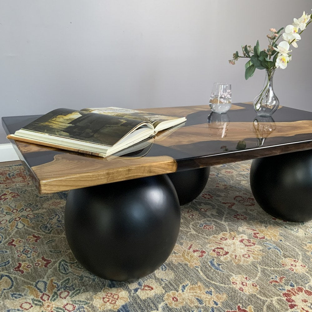 Close side view of the epoxy river coffee table with a large black ball leg in the foreground