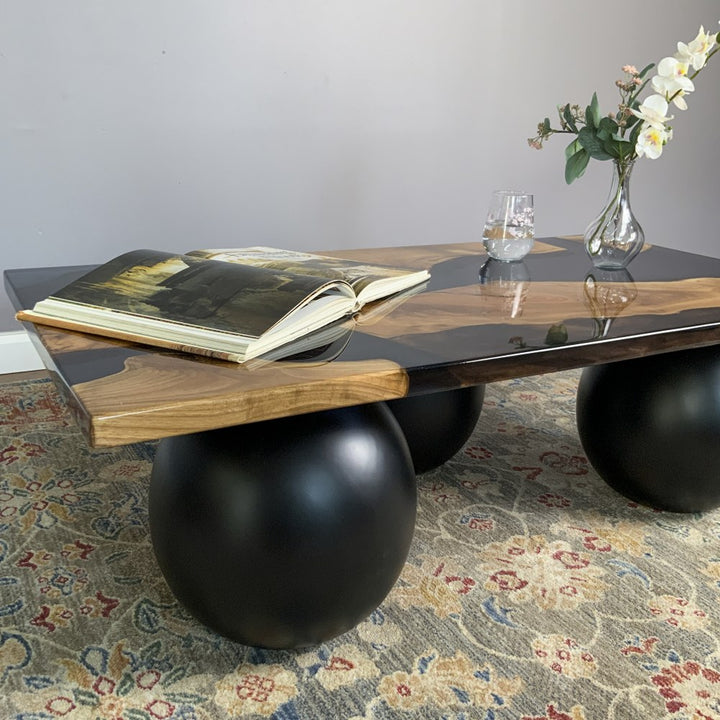 Close side view of the epoxy river coffee table with a large black ball leg in the foreground