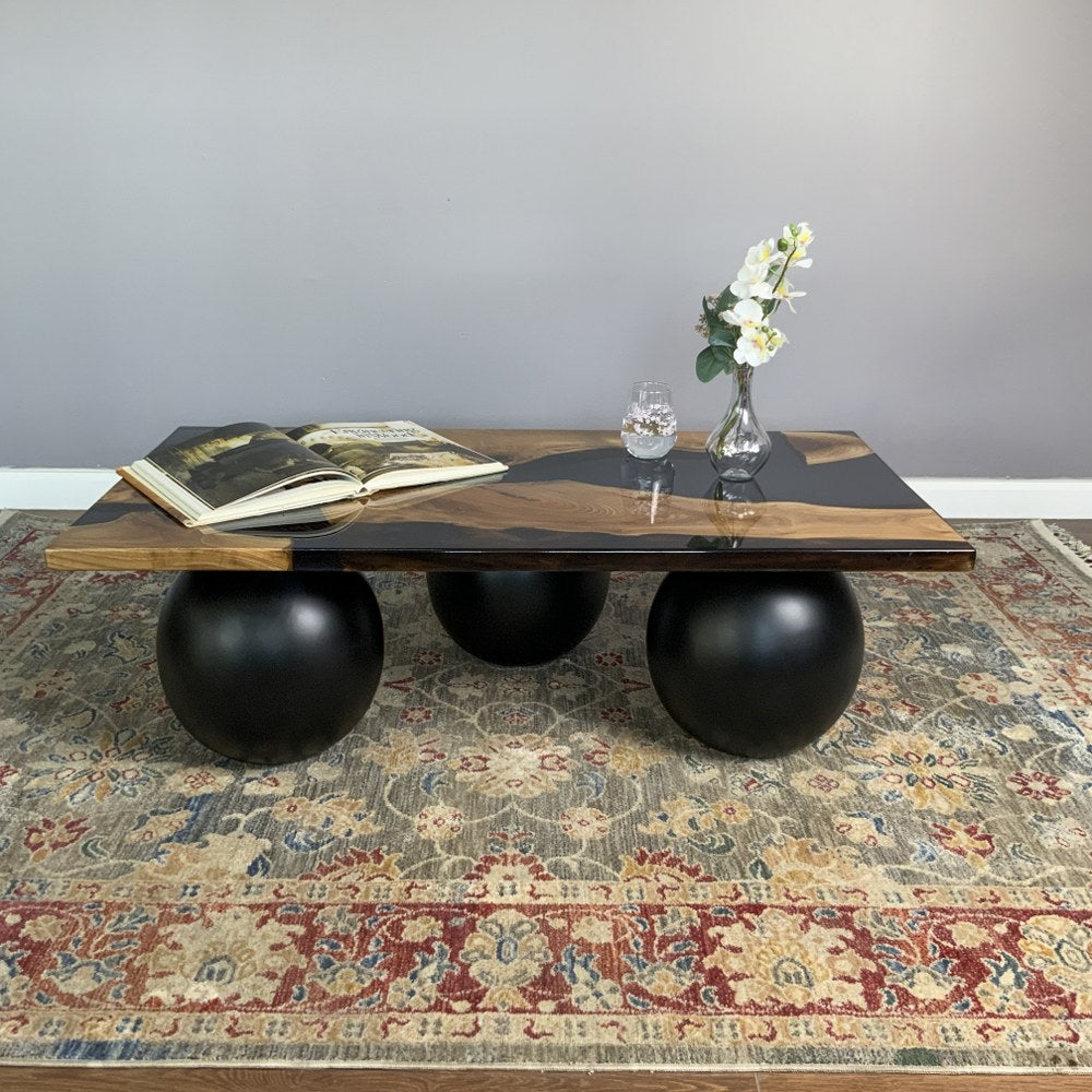 Low front view from the left of the black epoxy river coffee table with its ball legs