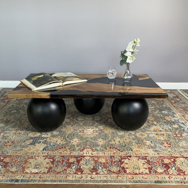 Low front view from the left of the black epoxy river coffee table with its ball legs