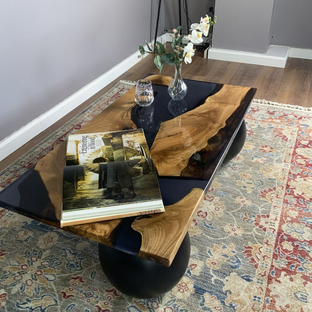 Three-quarter view of the black epoxy river coffee table from above on a woven rug