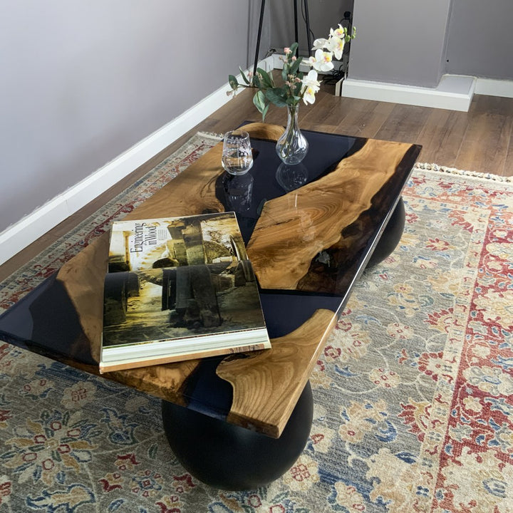 Three-quarter view of the black epoxy river coffee table from above on a woven rug