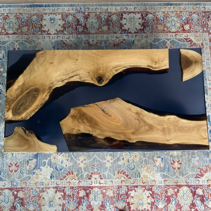 Top-down view of the walnut coffee table's black epoxy river between two live edge slabs