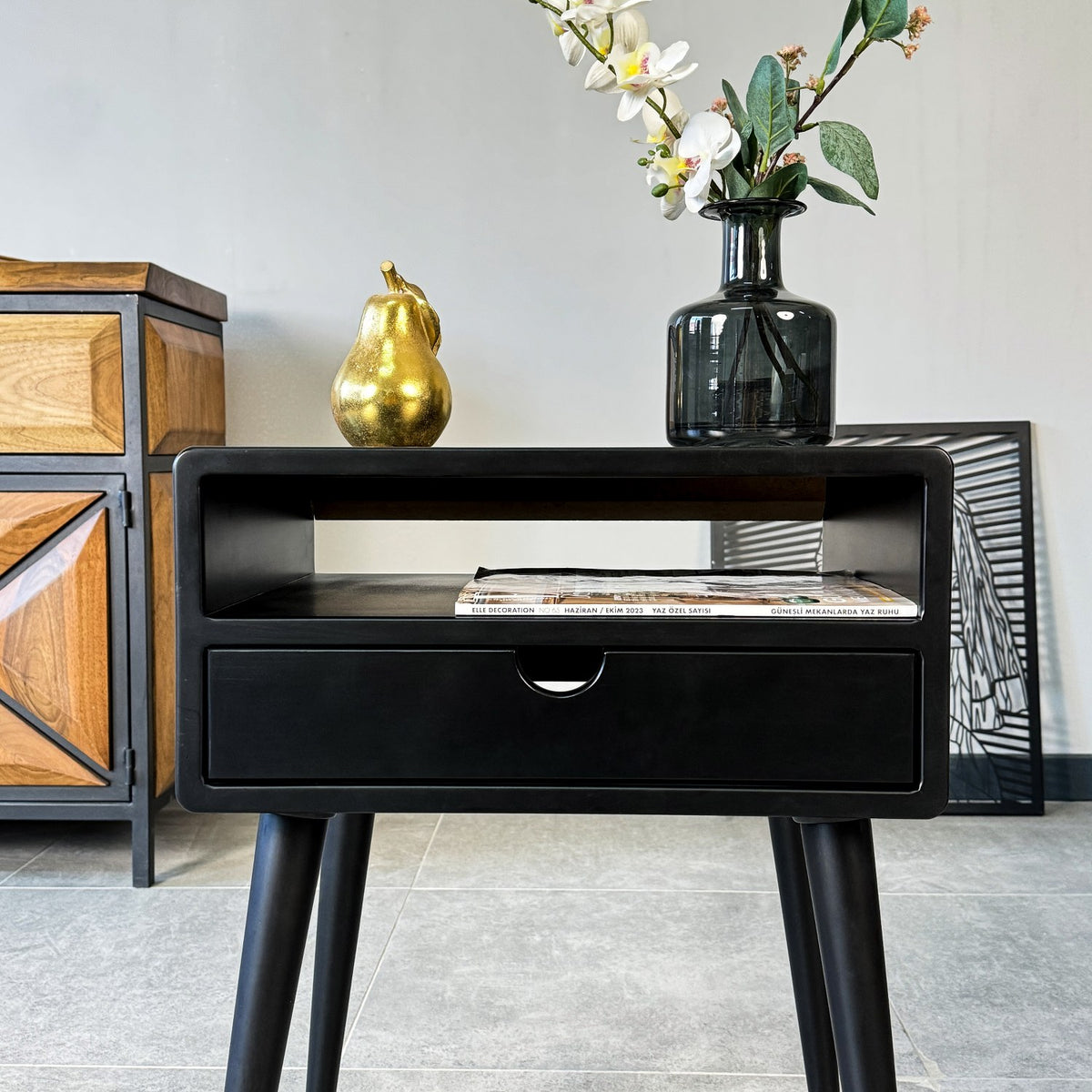 Close-up of the black side table front showing the open shelf and the drawer with a cut-out pull