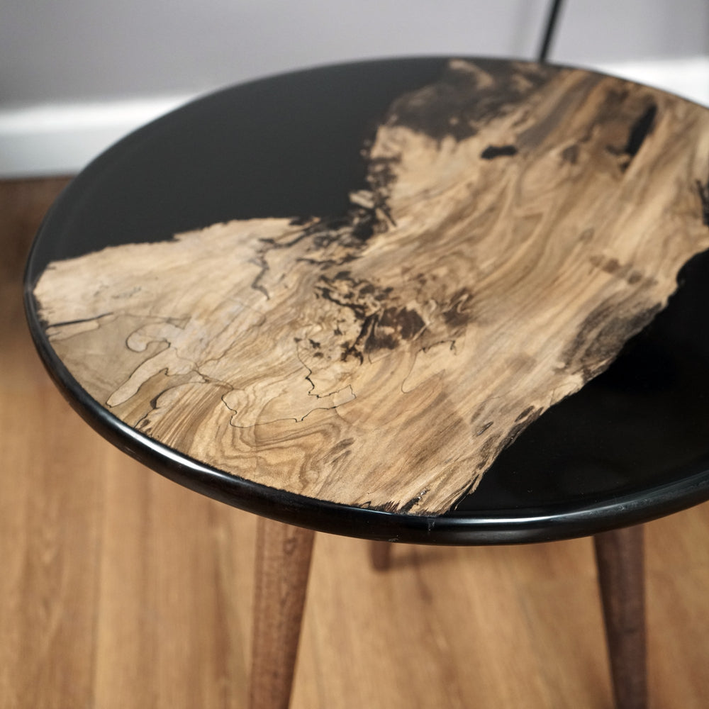 Close-up of the walnut island set in the black epoxy round top above the tapered legs