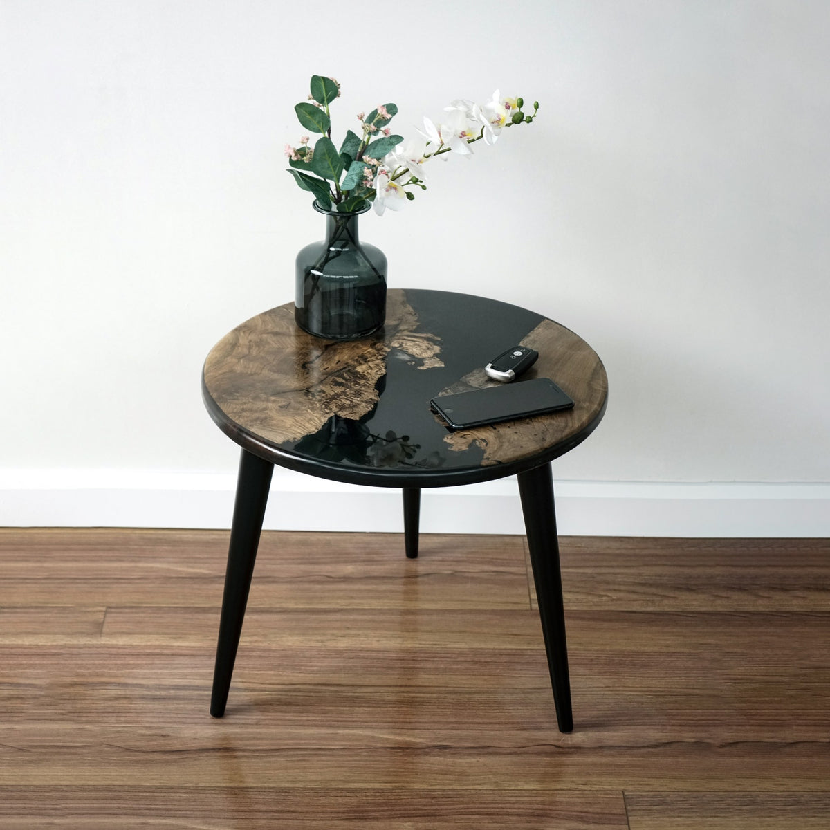 Round walnut epoxy side table with black tapered legs and River pattern top, front view
