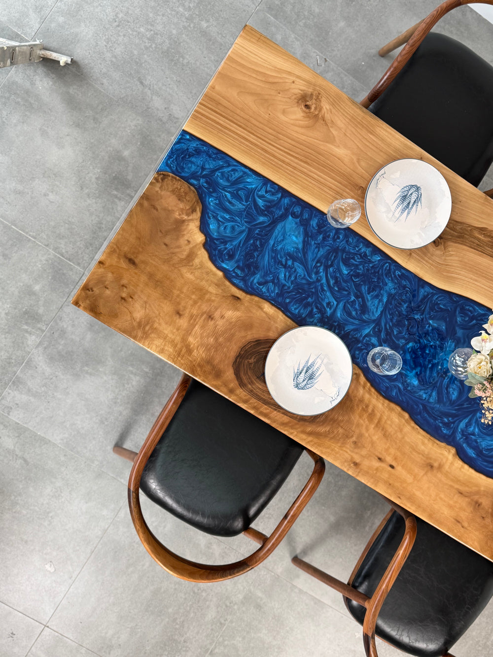 Overhead angled close-up of the blue epoxy river between walnut live edge slabs and a place setting
