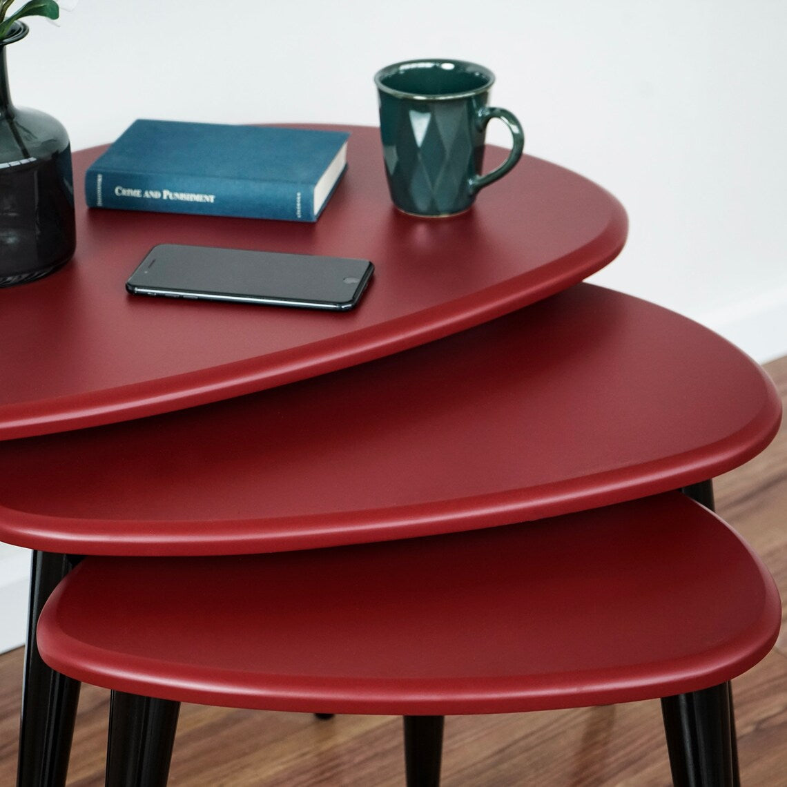 Close-up of the graduated burgundy pebble table tops with a book and mug on the top one