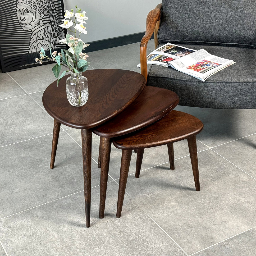 Solid oak Ercol style nest of three tables in chocolate oak with tapered legs and a vase on top