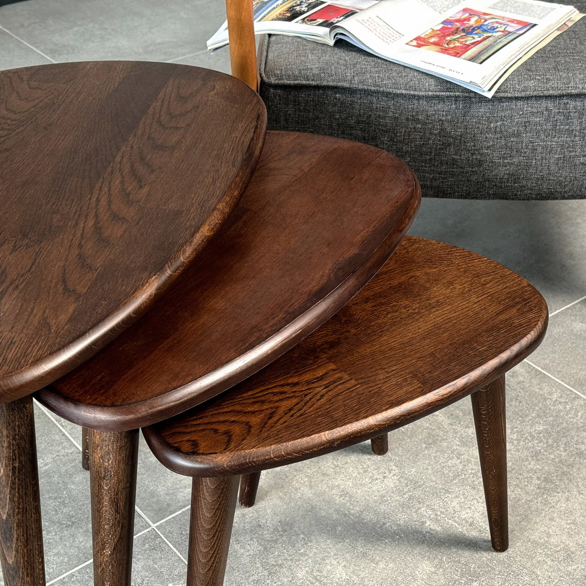 Close-up of the stacked pebble-shaped tops of the chocolate oak nest of tables showing oak grain