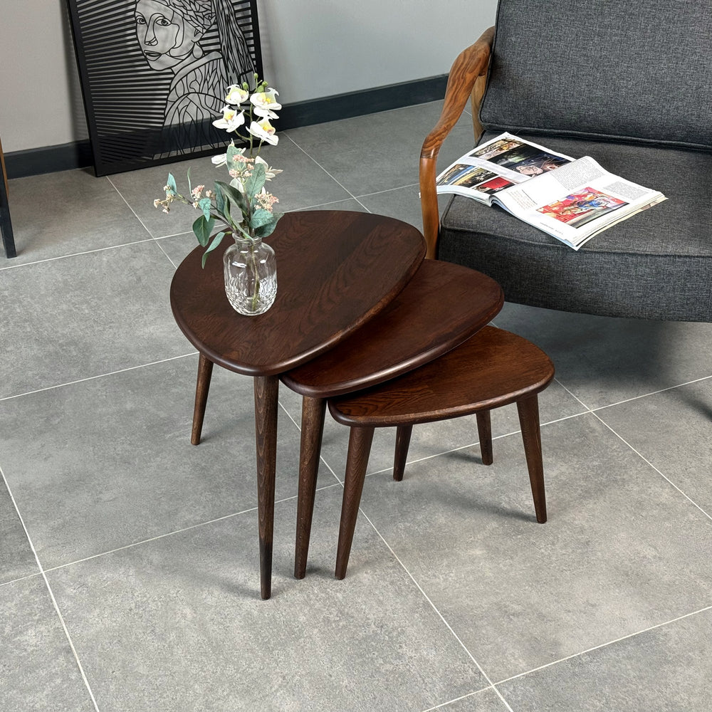Chocolate oak nesting tables from the front left, with an open magazine on the armchair behind
