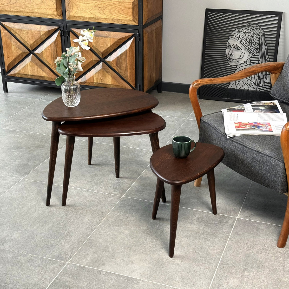 Chocolate oak nesting tables with the smallest table pulled out, beside a wooden cabinet