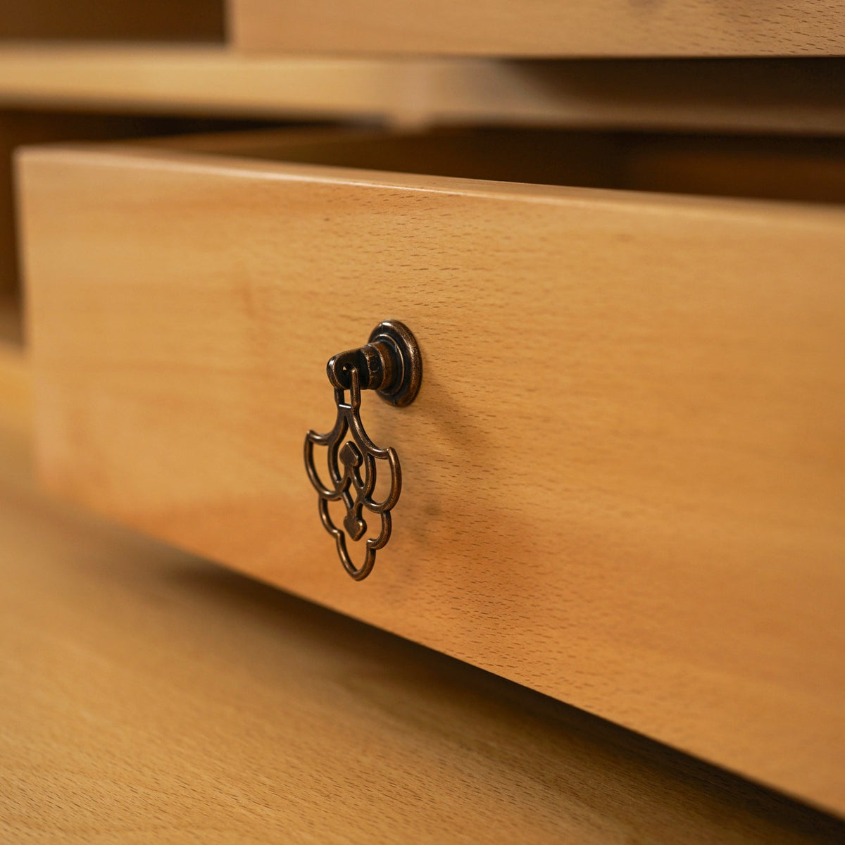 Close-up of an open drawer front with an antique-style drop pull on the beech writing desk