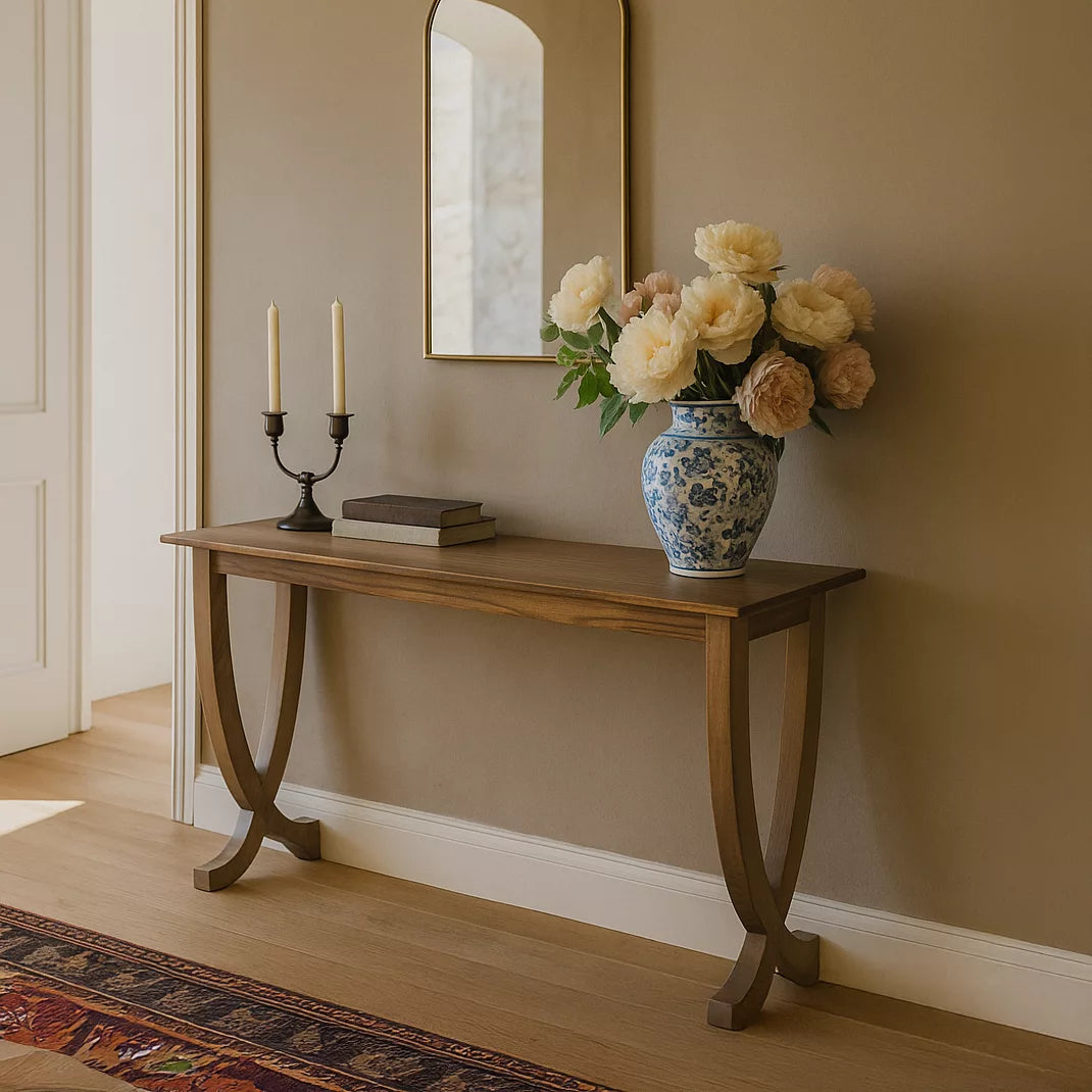 Walnut console table with curved legs under a mirror in a hallway on a patterned runner