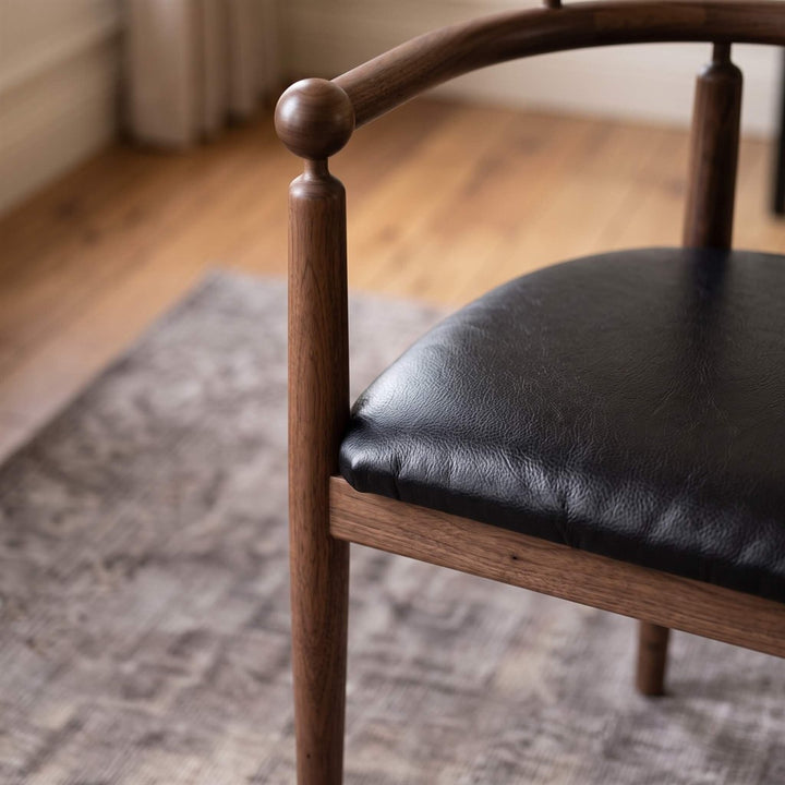 Solid walnut wood dining armchair with handcrafted turned wood details and padded seat for dining room interiors   