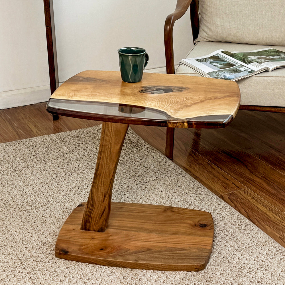 Light Brown walnut C shaped side table seen from the side with a curved pedestal and flat base
