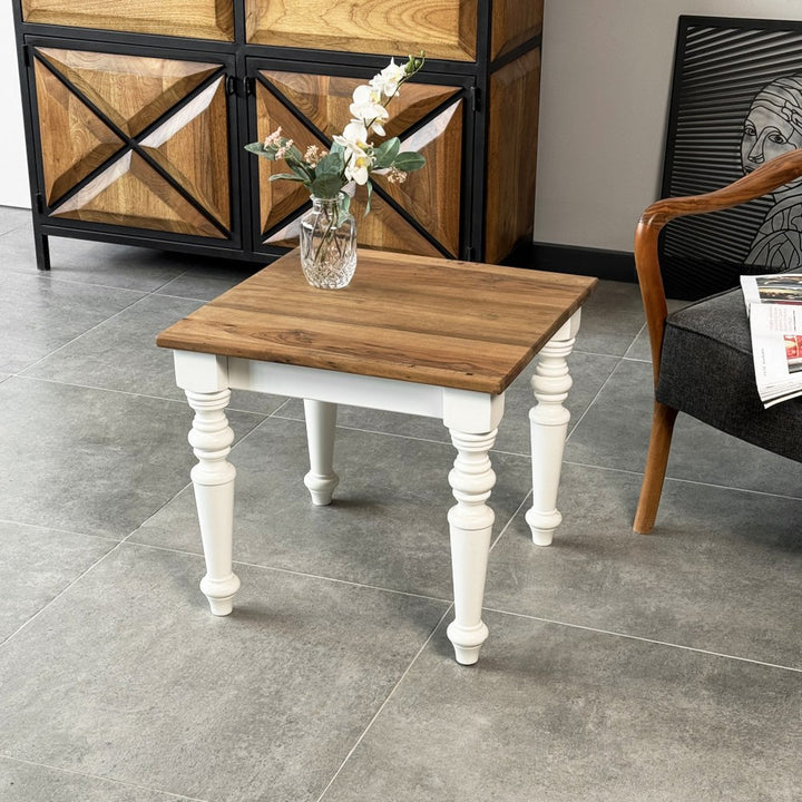 Walnut side table with white turned legs seen from the front corner beside an armchair