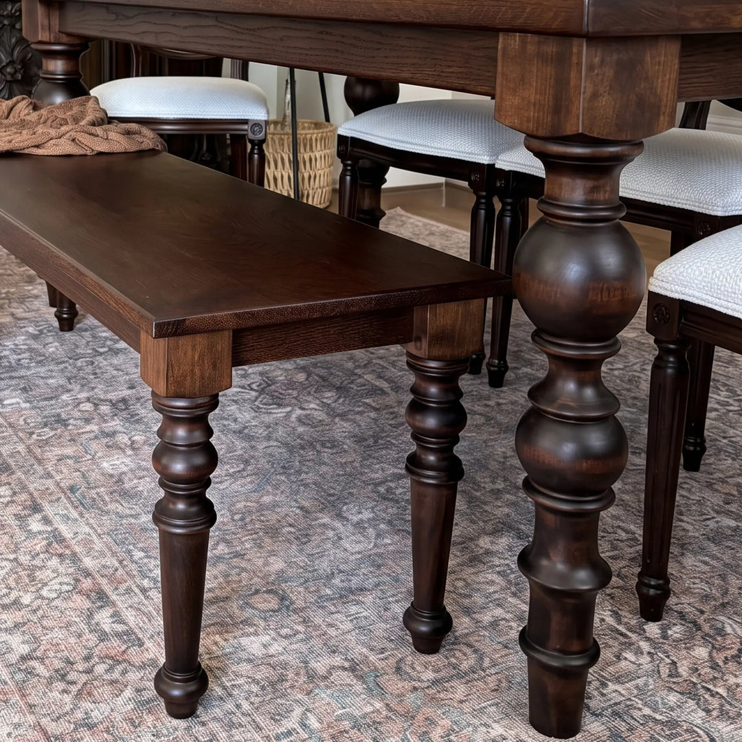 Corner view showing the oak tabletop edge, apron, and the block where the baluster leg meets the frame.