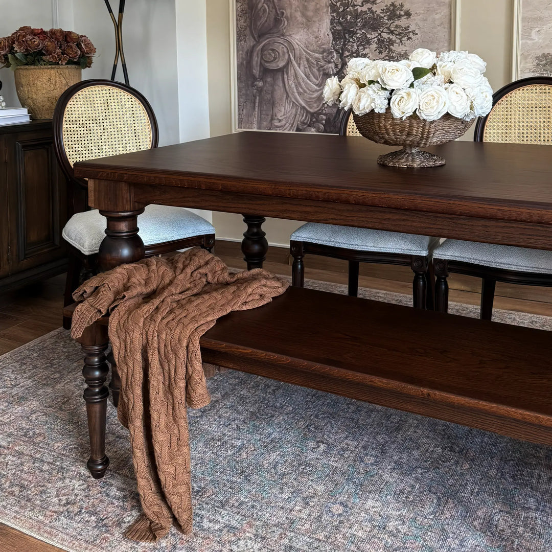 French country oak dining table with baluster legs, styled with cane back chairs and a matching bench in a formal dining room.